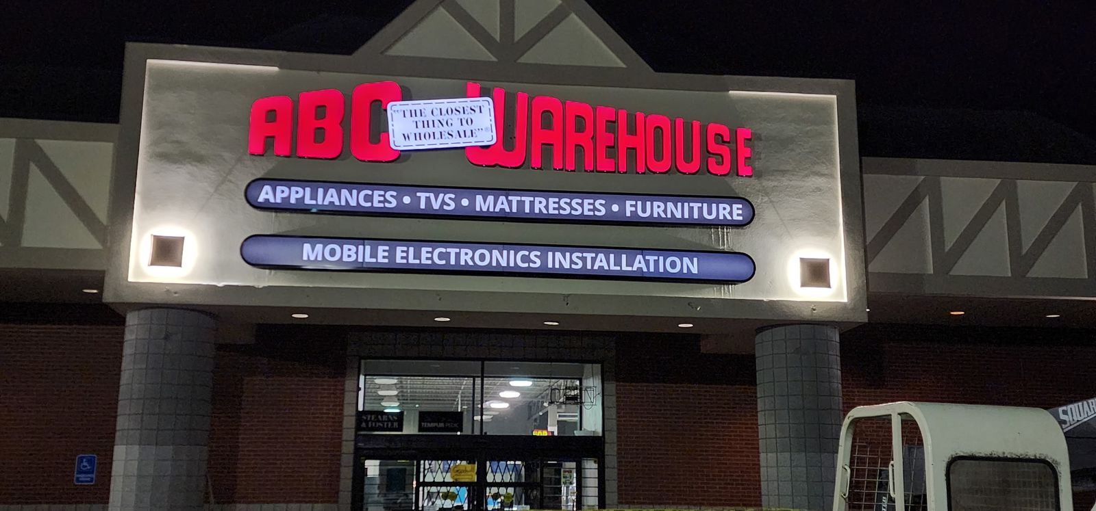 ABC Warehouse illuminated storefront sign at night