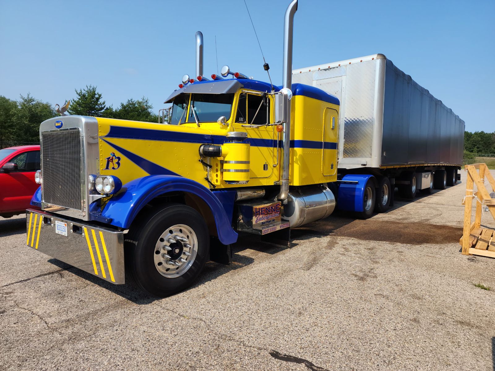 Yellow Peterbilt semi with blue stripe graphics and a trailer