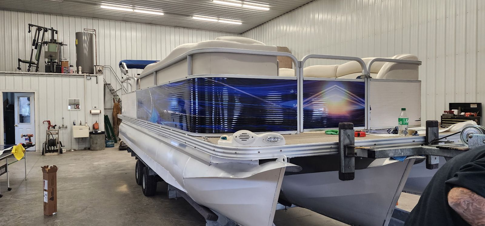 Pontoon boat with blue printed wrap graphics seen from the front corner
