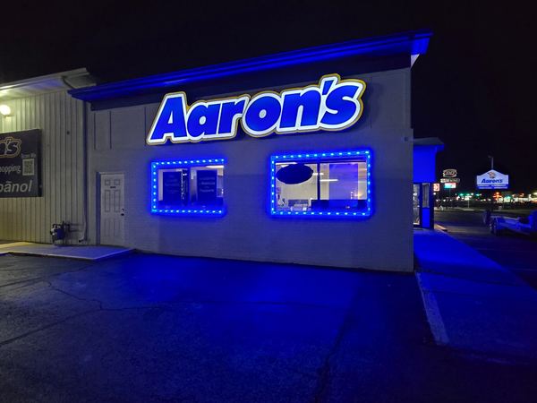 Aaron's blue illuminated channel letter sign on a storefront at night