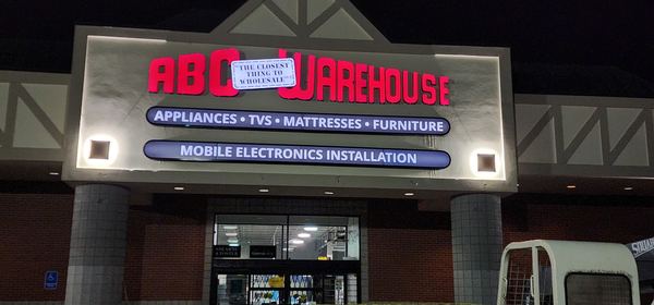 ABC Warehouse illuminated storefront sign at night
