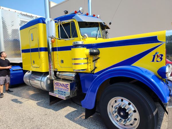 Close-up of a yellow Peterbilt with blue stripes and number 13 graphics