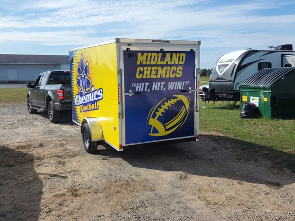 Rear of an enclosed trailer wrapped with Midland Chemics Football graphics