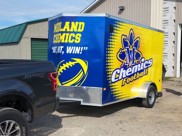 Enclosed trailer wrapped in blue and yellow Midland Chemics Football graphics