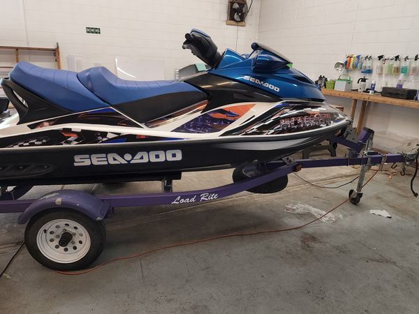 Sea-Doo jet ski with blue and black custom graphics on a trailer, side view