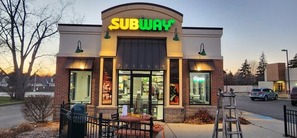 Subway restaurant storefront with lit signs at dusk